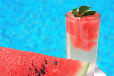 Photo of Refreshing drink in glass and sliced watermelon near swimming pool outdoors, closeup