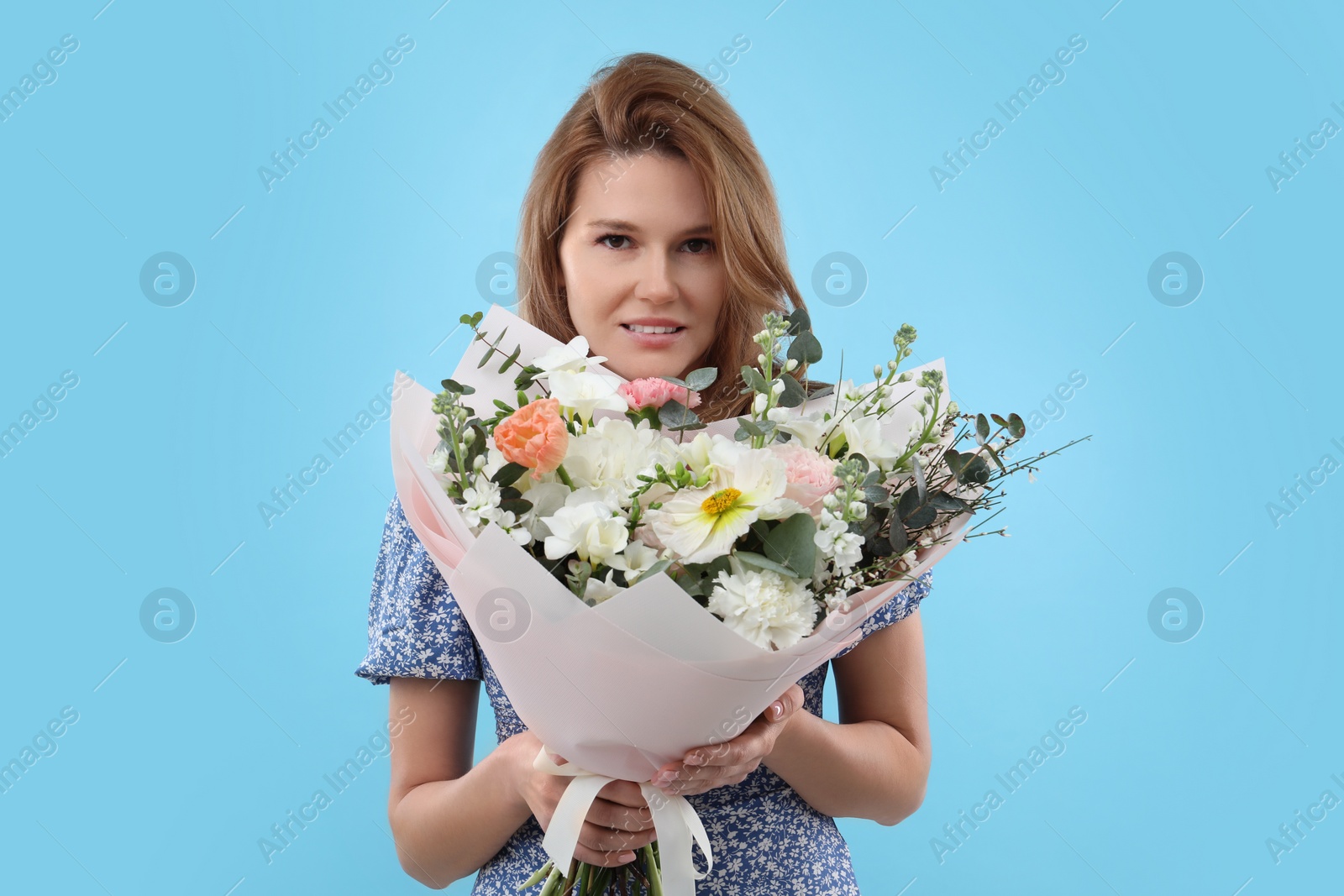 Photo of Beautiful woman with bouquet of flowers on light blue background