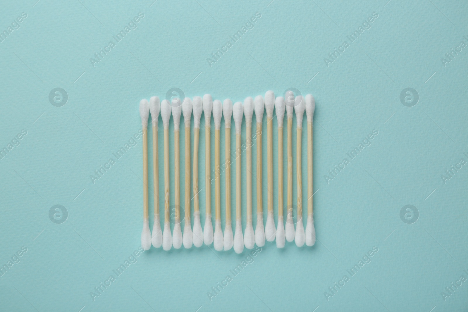 Photo of Many wooden cotton buds on turquoise background, flat lay