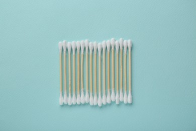 Many wooden cotton buds on turquoise background, flat lay