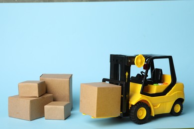 Photo of Toy forklift with boxes on blue background. Logistics and wholesale concept