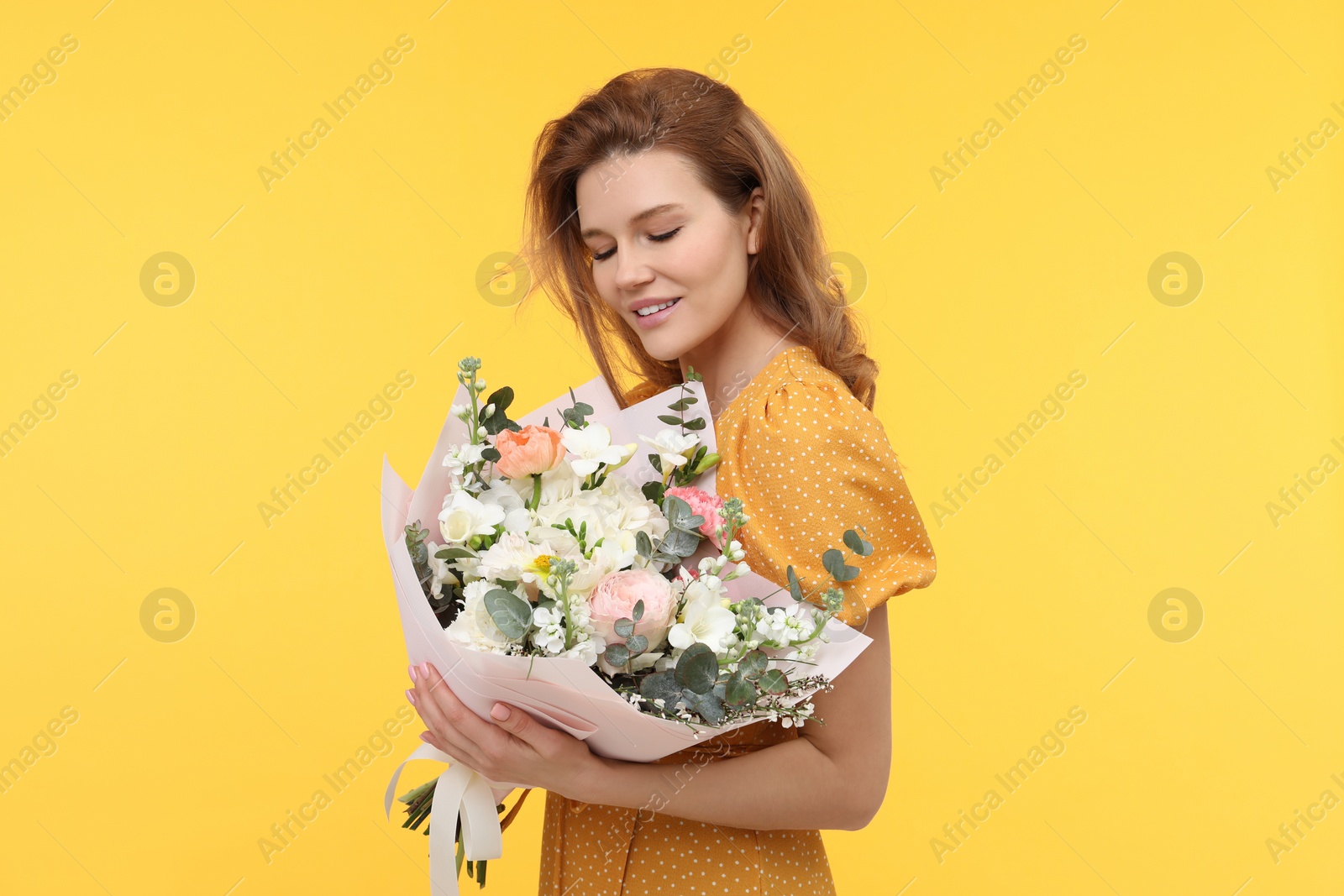 Photo of Happy woman with bouquet of beautiful flowers on yellow background