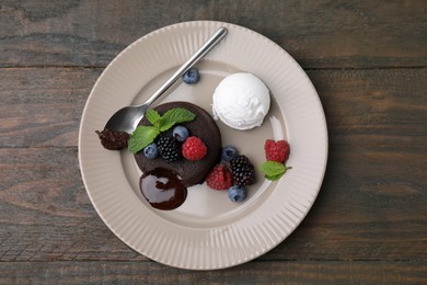 Photo of Delicious chocolate fondant served with fresh berries and ice cream on wooden table, top view