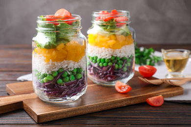 Photo of Healthy salad in glass jars on wooden table