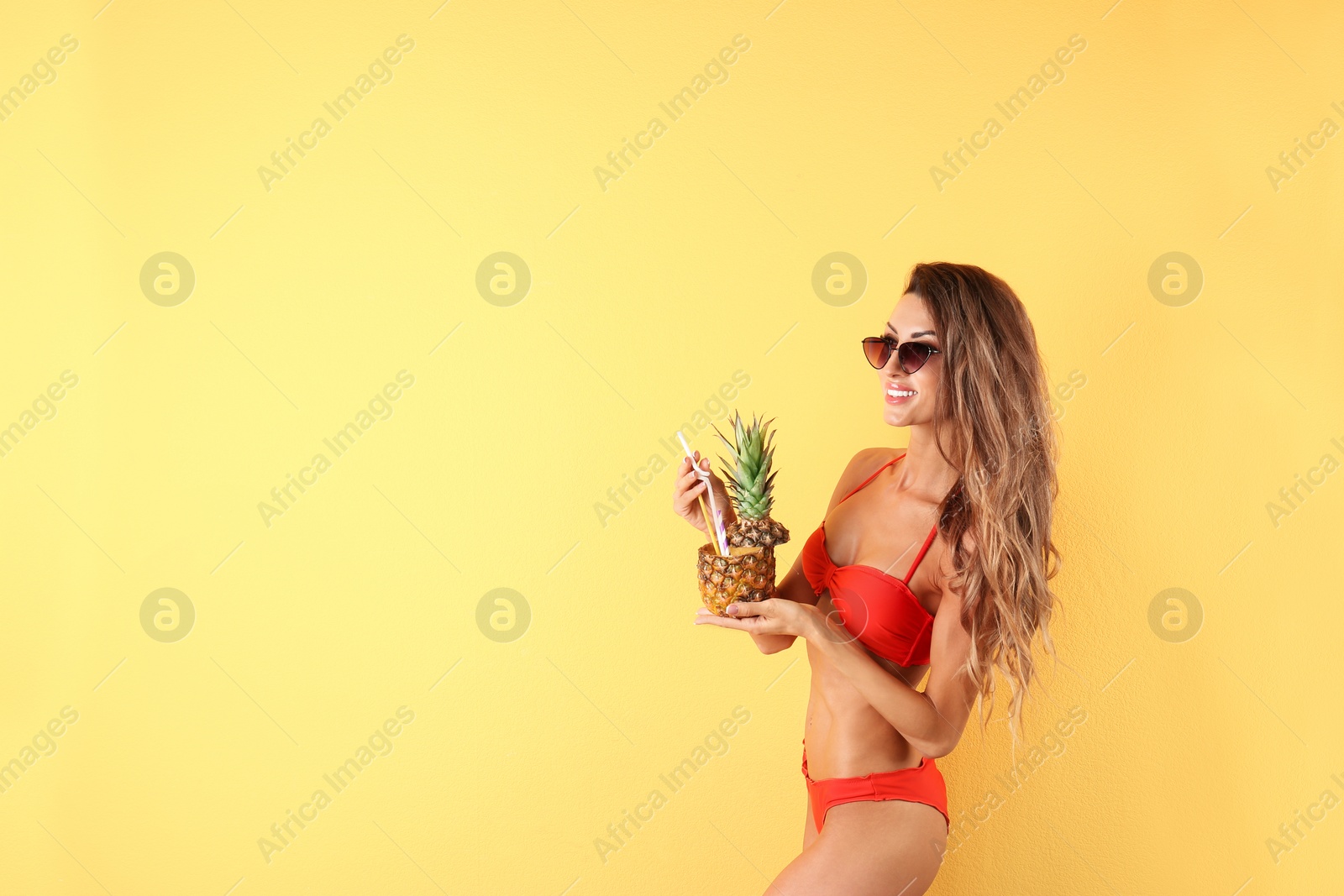 Photo of Pretty sexy woman in stylish bikini with cocktail on color background, space for text