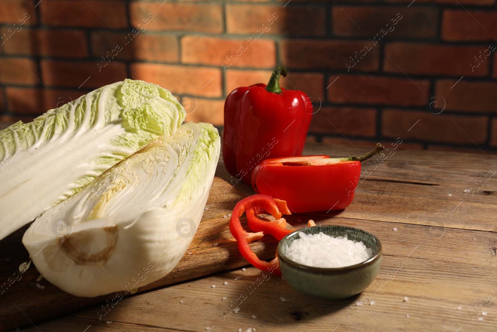 Photo of Fresh Chinese cabbages, bell peppers and salt on wooden table