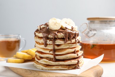 Photo of Tasty pancakes with sliced banana served on white table