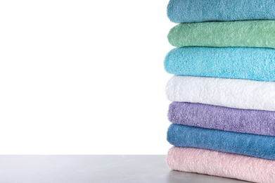 Photo of Fresh towels on light grey table against white background. Space for text