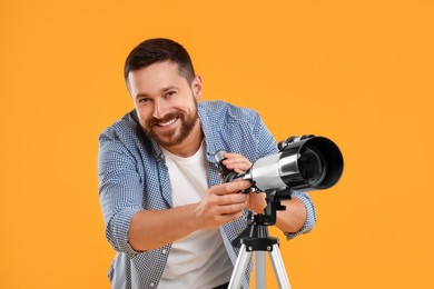 Happy astronomer with telescope on orange background