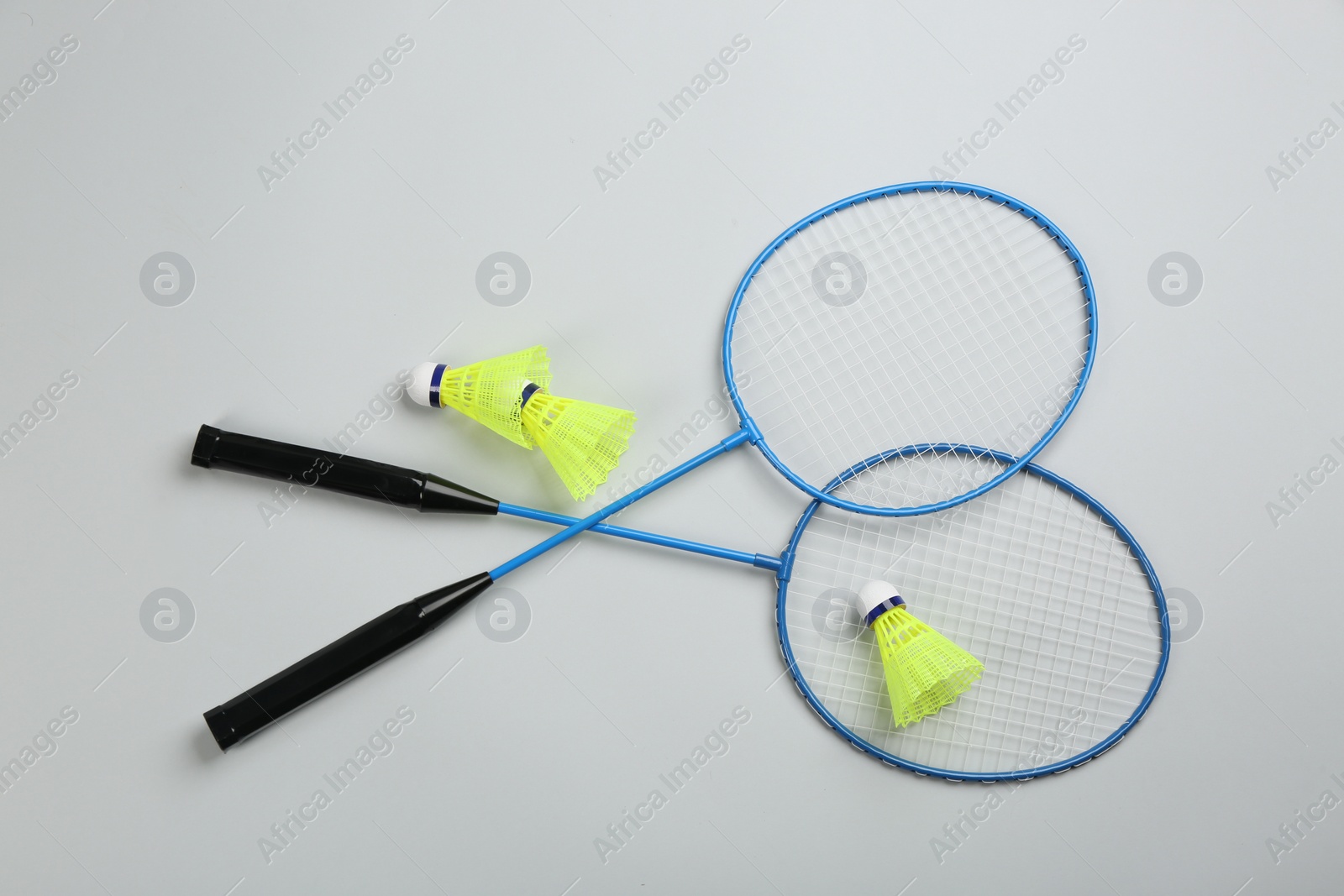 Photo of Rackets and shuttlecocks on light grey background, flat lay. Badminton equipment