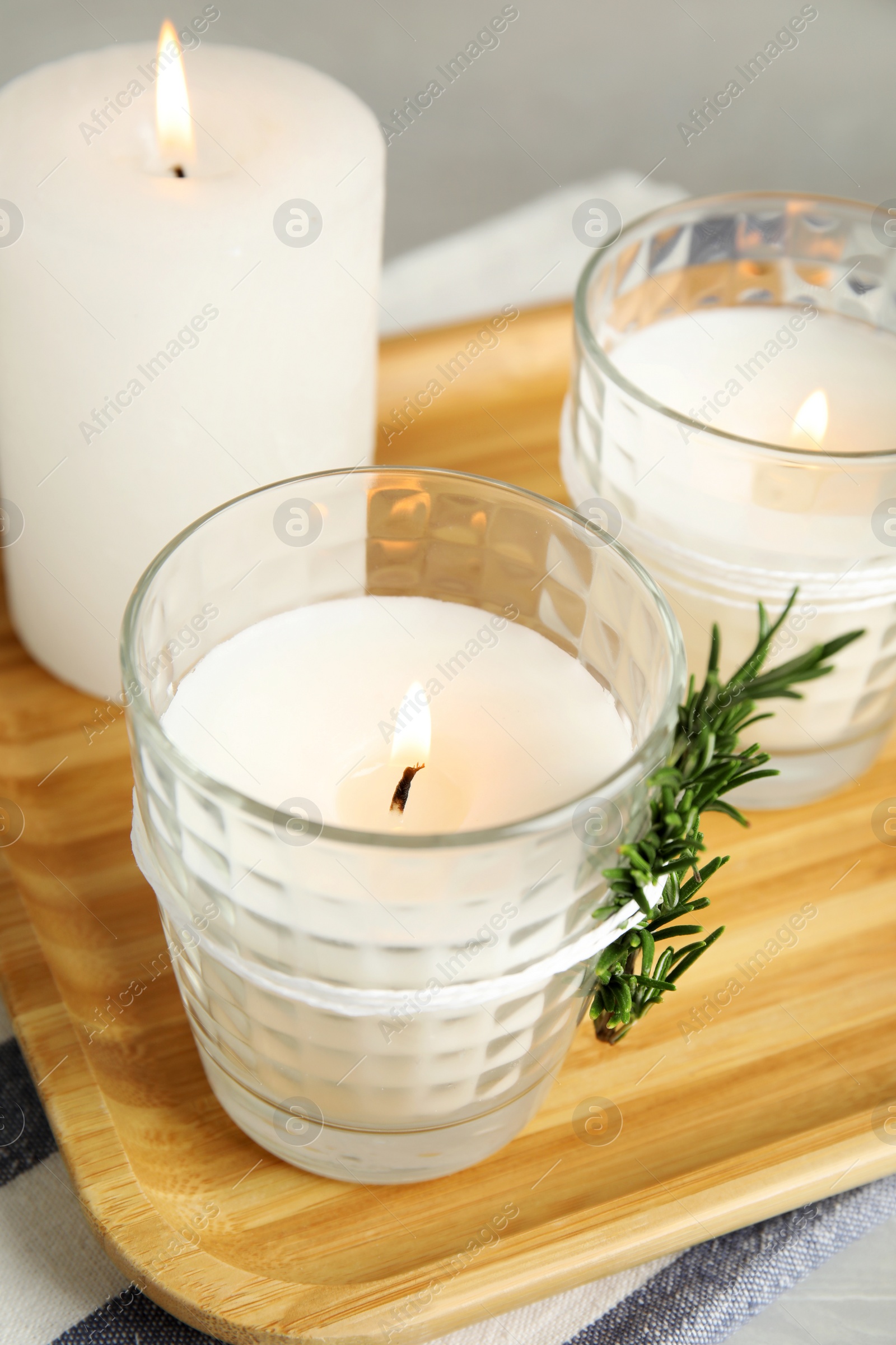 Photo of Wooden tray with burning candles on table