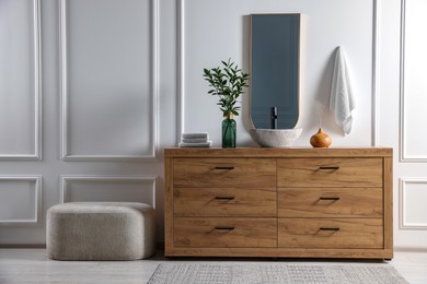 Photo of Modern bathroom interior with stylish mirror, eucalyptus branches, wooden vanity and pouf