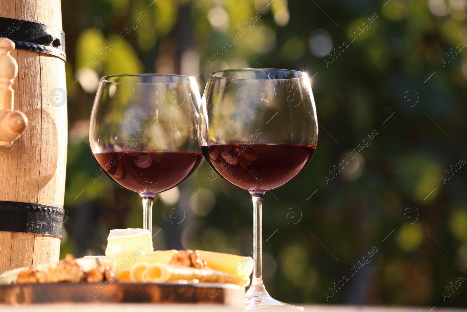 Photo of Glasses with red wine on table outdoors. Space for text