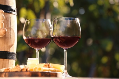 Photo of Glasses with red wine on table outdoors. Space for text