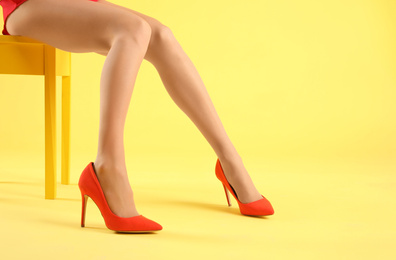 Photo of Woman wearing tights and stylish red shoes on yellow background, closeup