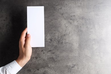 Photo of Man holding blank card at black textured table, top view. Mockup for design