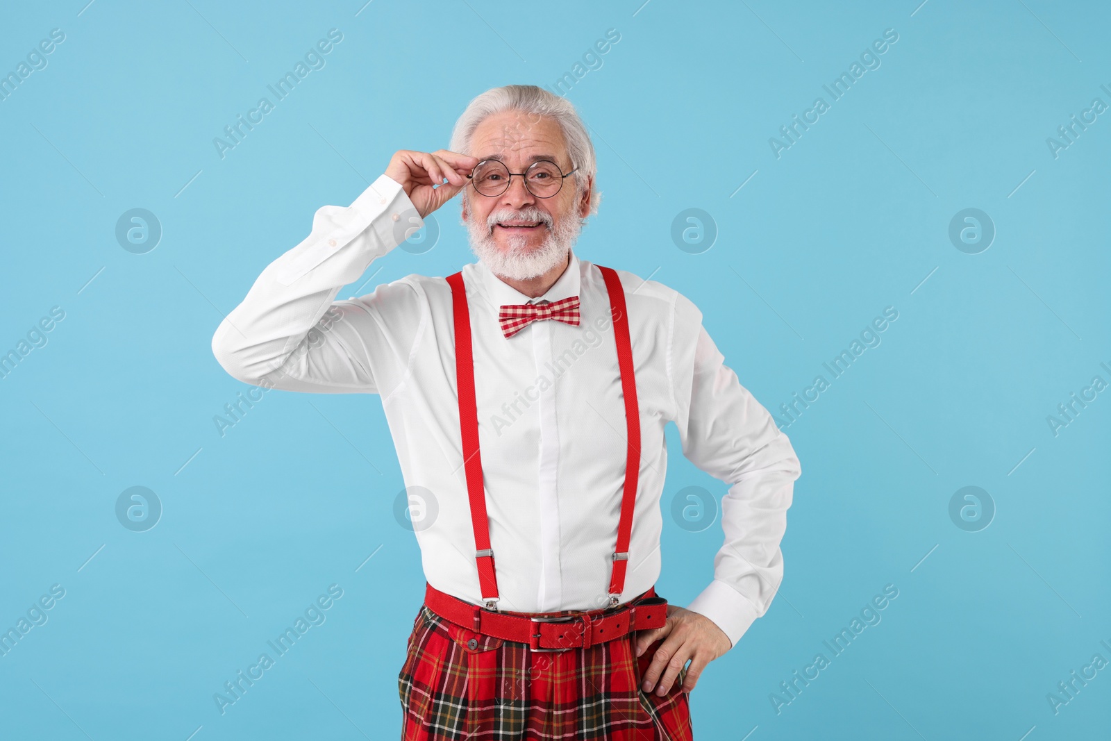 Photo of Portrait of stylish grandpa with glasses and bowtie on light blue background