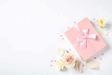 Photo of Pink gift box and beautiful flowers on white background, flat lay. Space for text