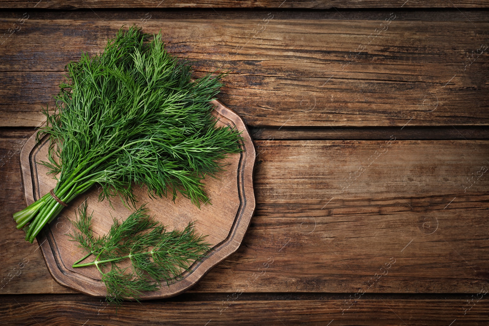 Photo of Bunch of fresh dill on wooden table, top view. Space for text