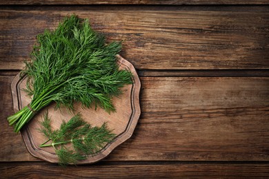 Photo of Bunch of fresh dill on wooden table, top view. Space for text