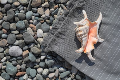 Photo of Sea shell and towel on stones outdoors, flat lay. Space for text