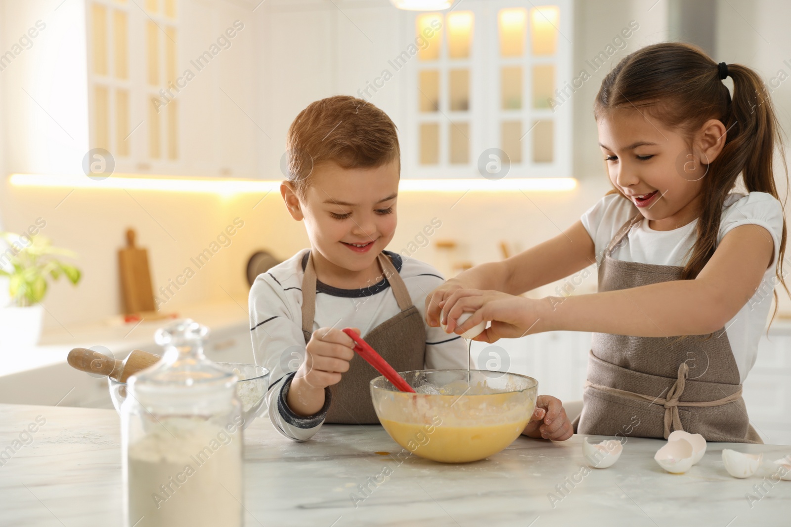 Photo of Cute little children cooking dough together in kitchen