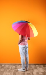 Man with rainbow umbrella near color wall