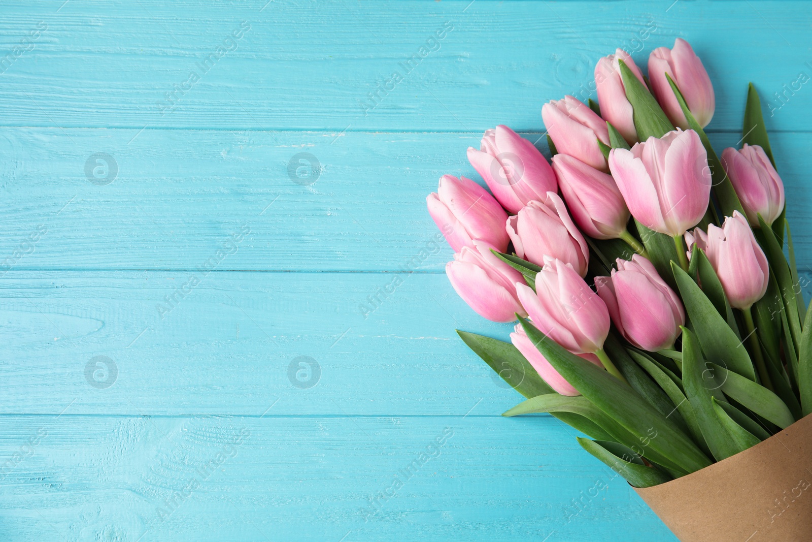 Photo of Beautiful pink spring tulips on light blue wooden background, top view. Space for text