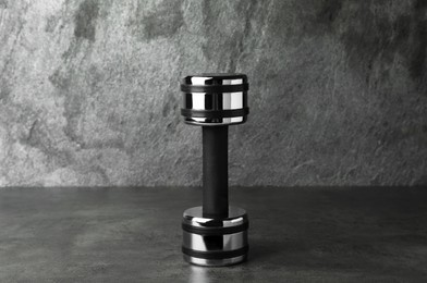 Photo of Metal dumbbell on table against grey background