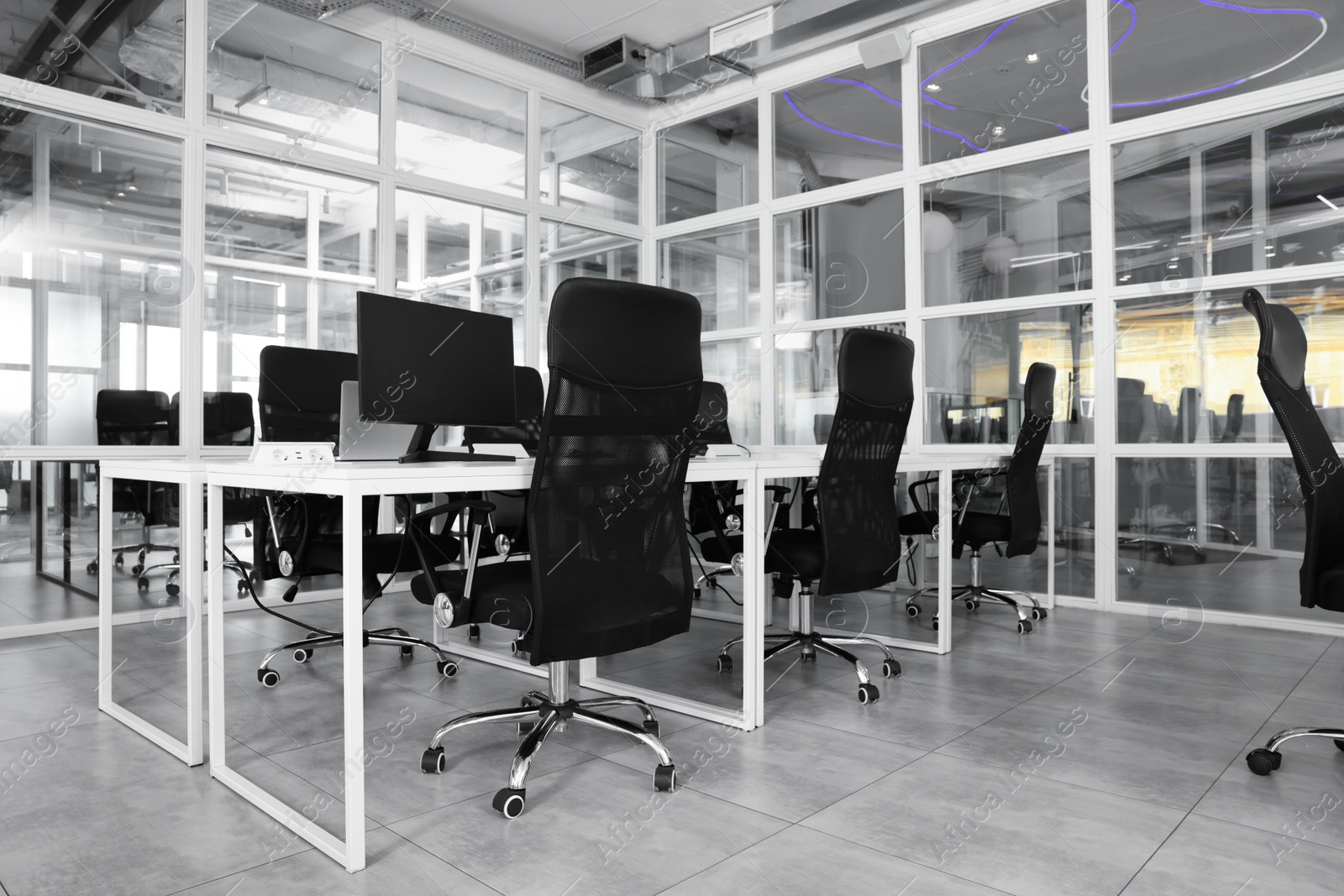 Photo of Stylish interior of open plan office. Workspace with computers, tables and chairs