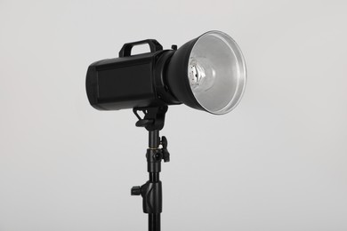 Photo of Studio flash light with reflector on grey background. Professional photographer's equipment