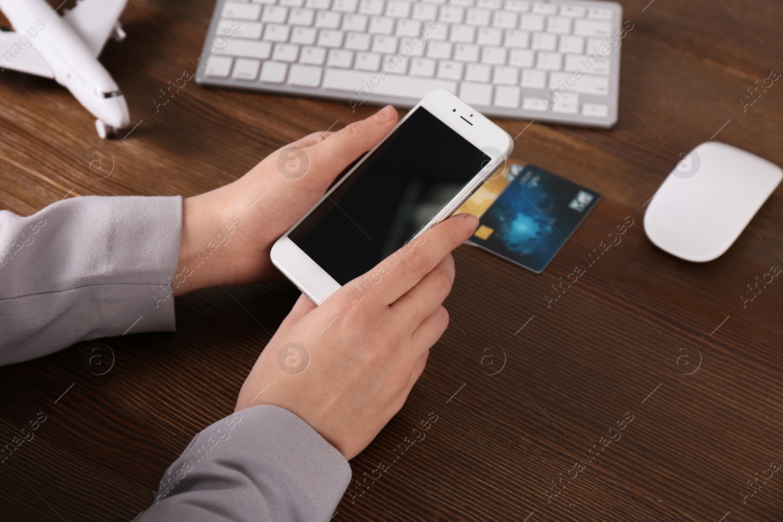 Photo of Woman using mobile phone at table in travel agency, closeup with space for design