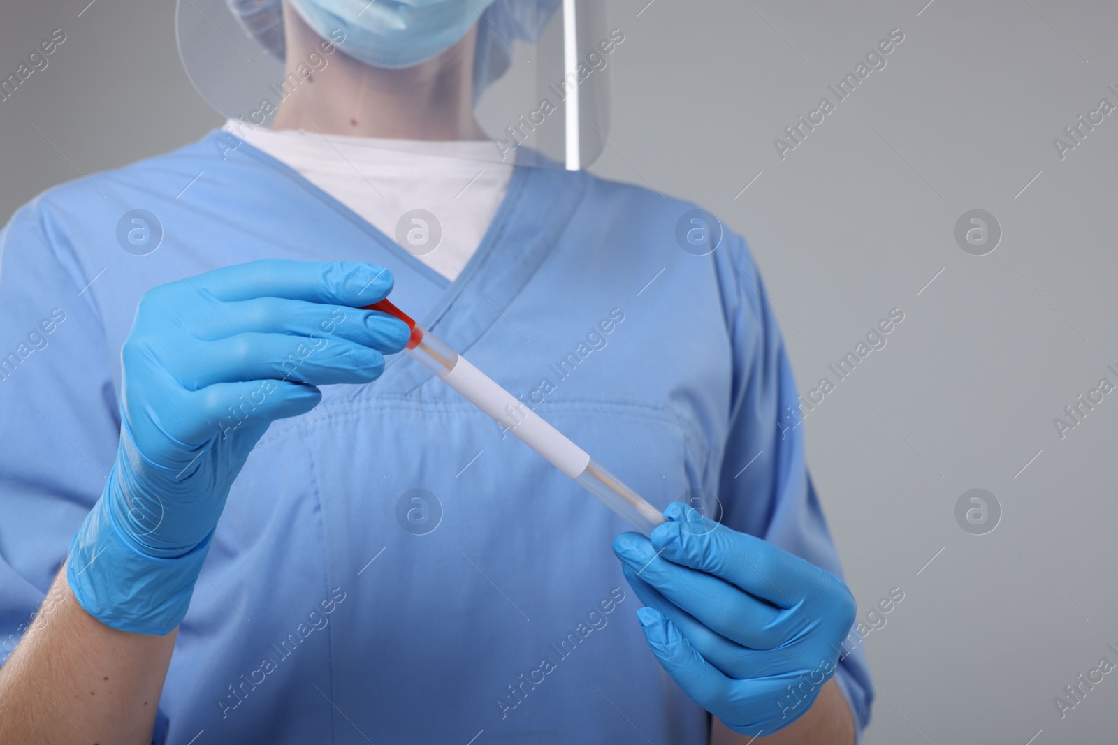 Photo of Laboratory testing. Doctor with cotton swab and tube on light grey background, closeup