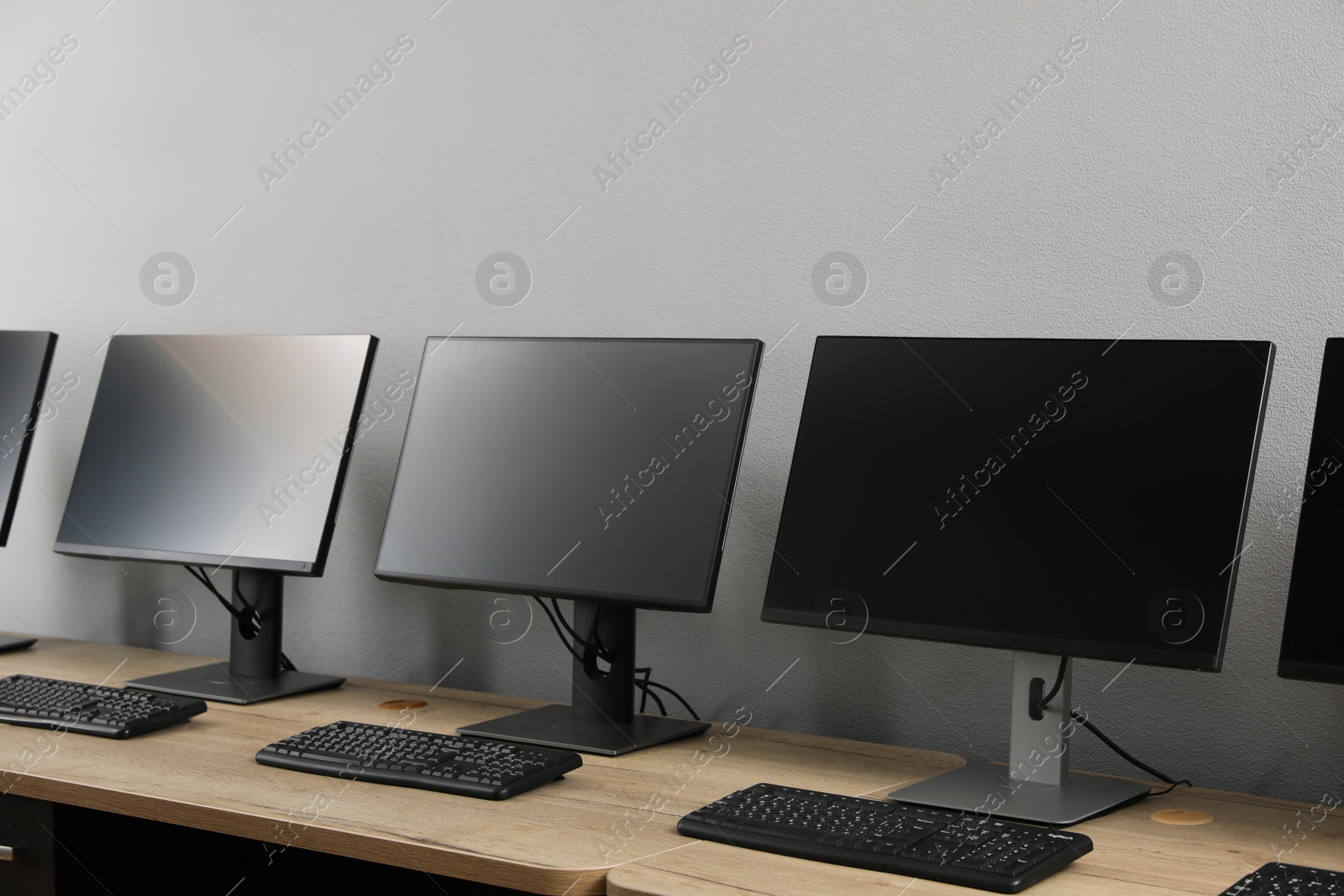 Photo of Open office interior. Modern workplaces with computers near light grey wall