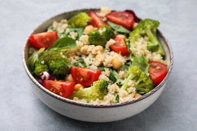 Photo of Healthy meal. Tasty salad with quinoa, chickpeas and vegetables on grey table, closeup