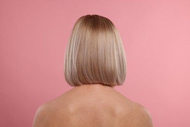 Woman with healthy skin on pink background, back view