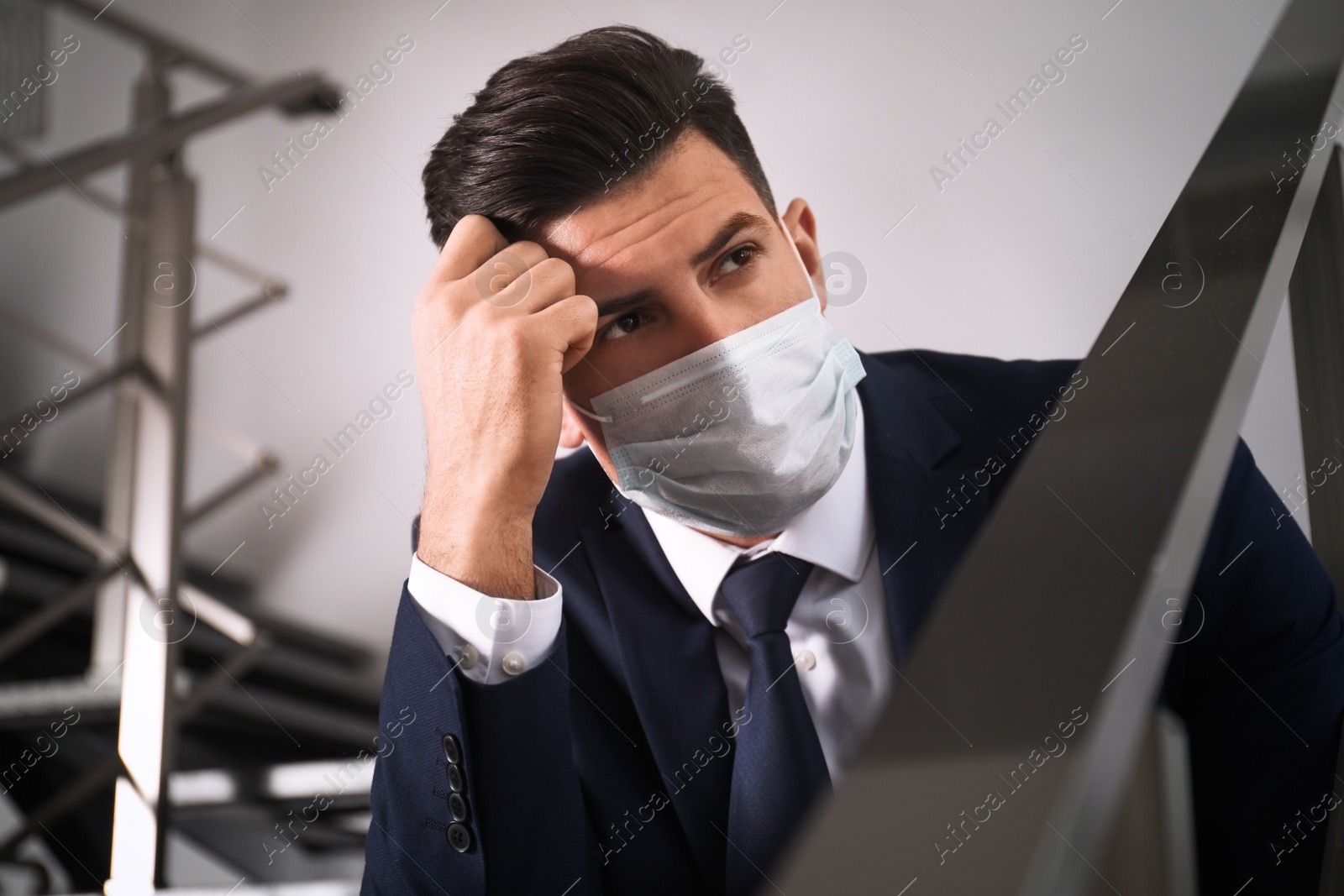 Photo of Sad man in protective mask on stairs indoors. Self-isolation during coronavirus pandemic