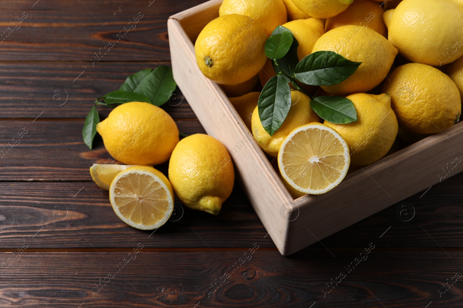 Photo of Fresh lemons in crate on wooden table