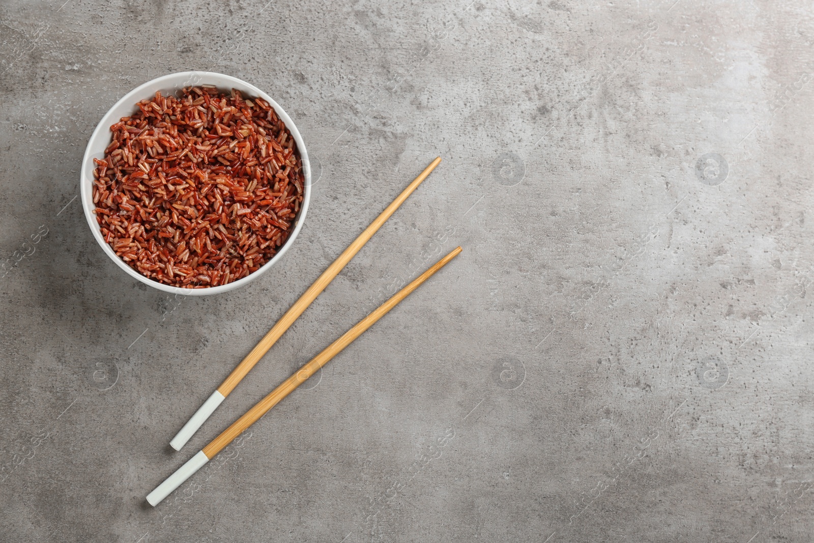 Photo of Delicious brown rice served on light table, flat lay. Space for text