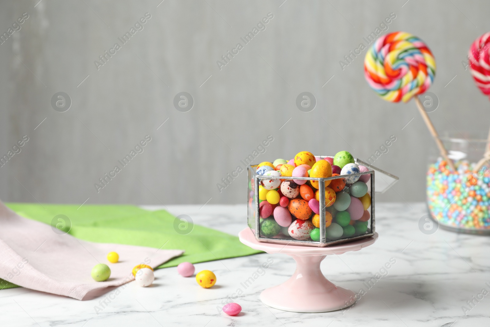 Photo of Delicious colorful dragee candies on white marble table, space for text