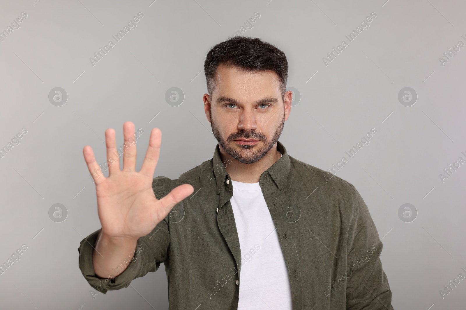 Photo of Handsome man showing stop gesture on light grey background