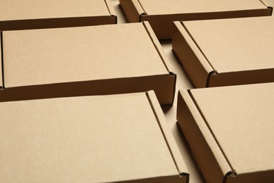 Photo of Many closed cardboard boxes on light brown background, closeup