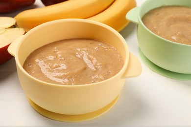 Photo of Bowls with banana puree on white table. Baby food