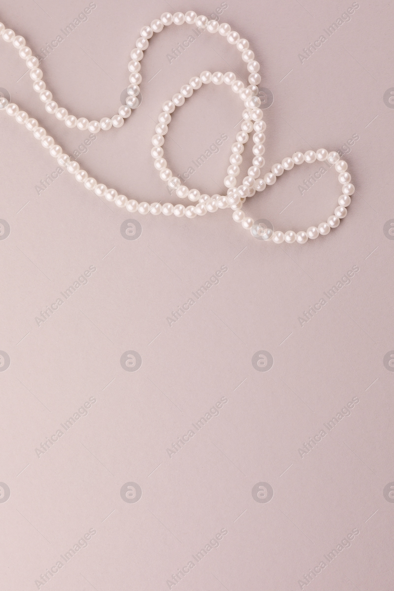 Photo of Elegant pearl necklace on beige background, top view. Space for text