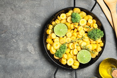 Photo of Raw yellow carrot with limes and broccoli on grey table, flat lay. Space for text