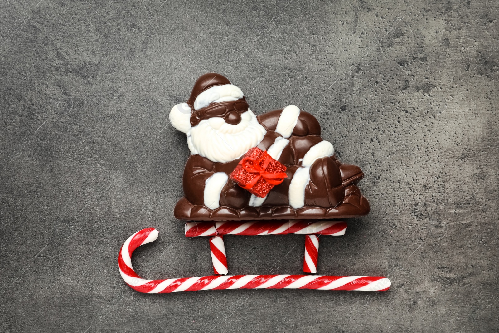 Photo of Flat lay composition with Santa Claus and candy canes on grey table