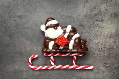 Flat lay composition with Santa Claus and candy canes on grey table