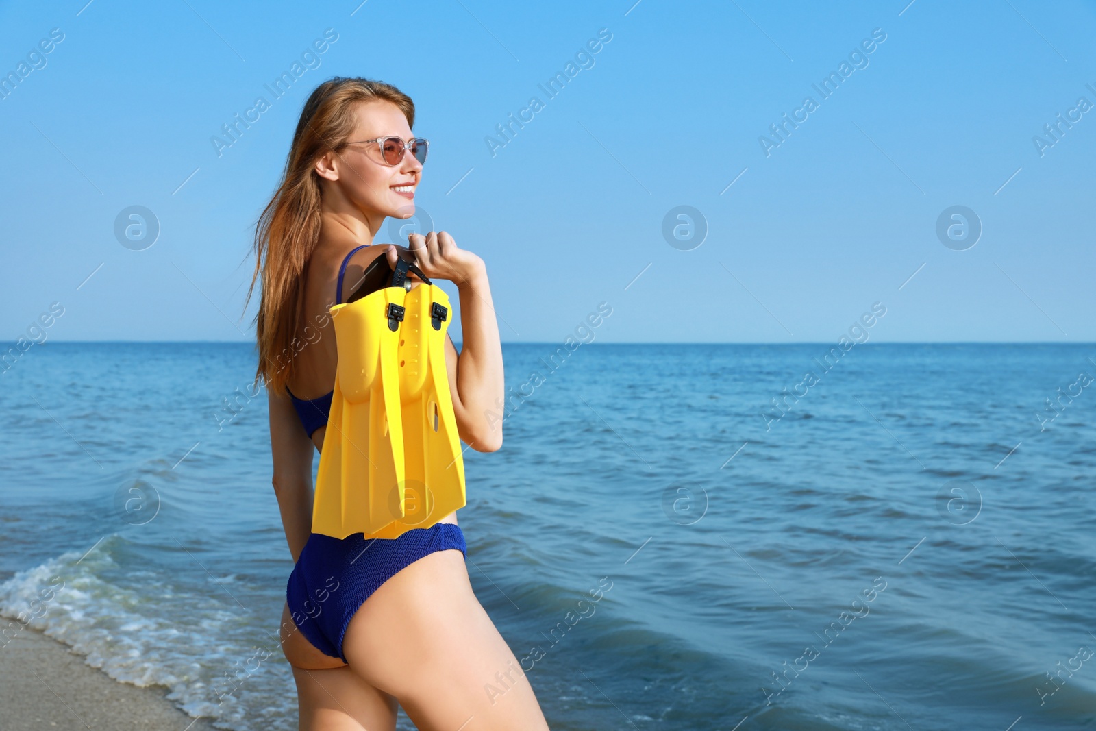 Photo of Happy woman with flippers near sea on beach