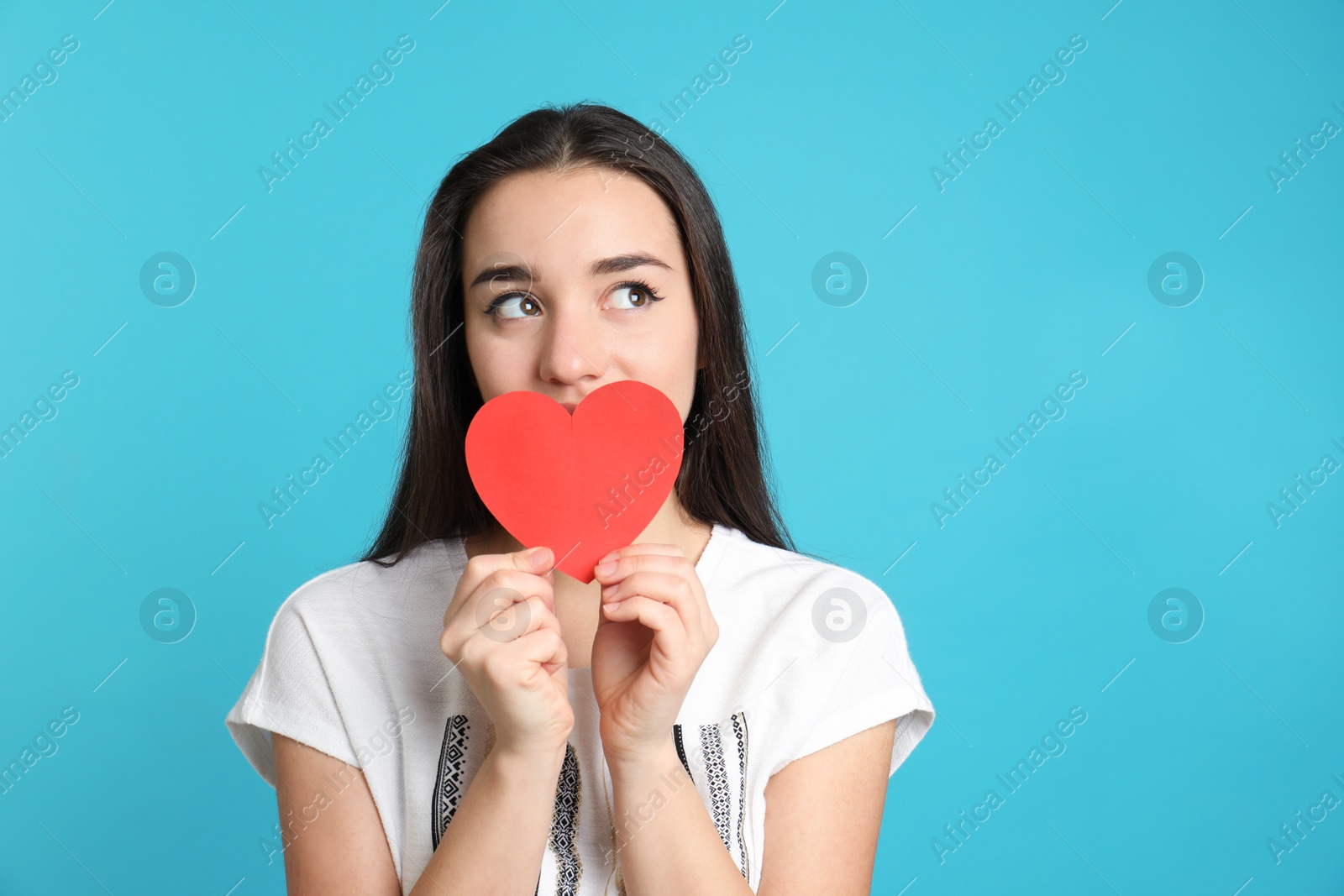 Photo of Portrait of beautiful young woman with paper heart on color background