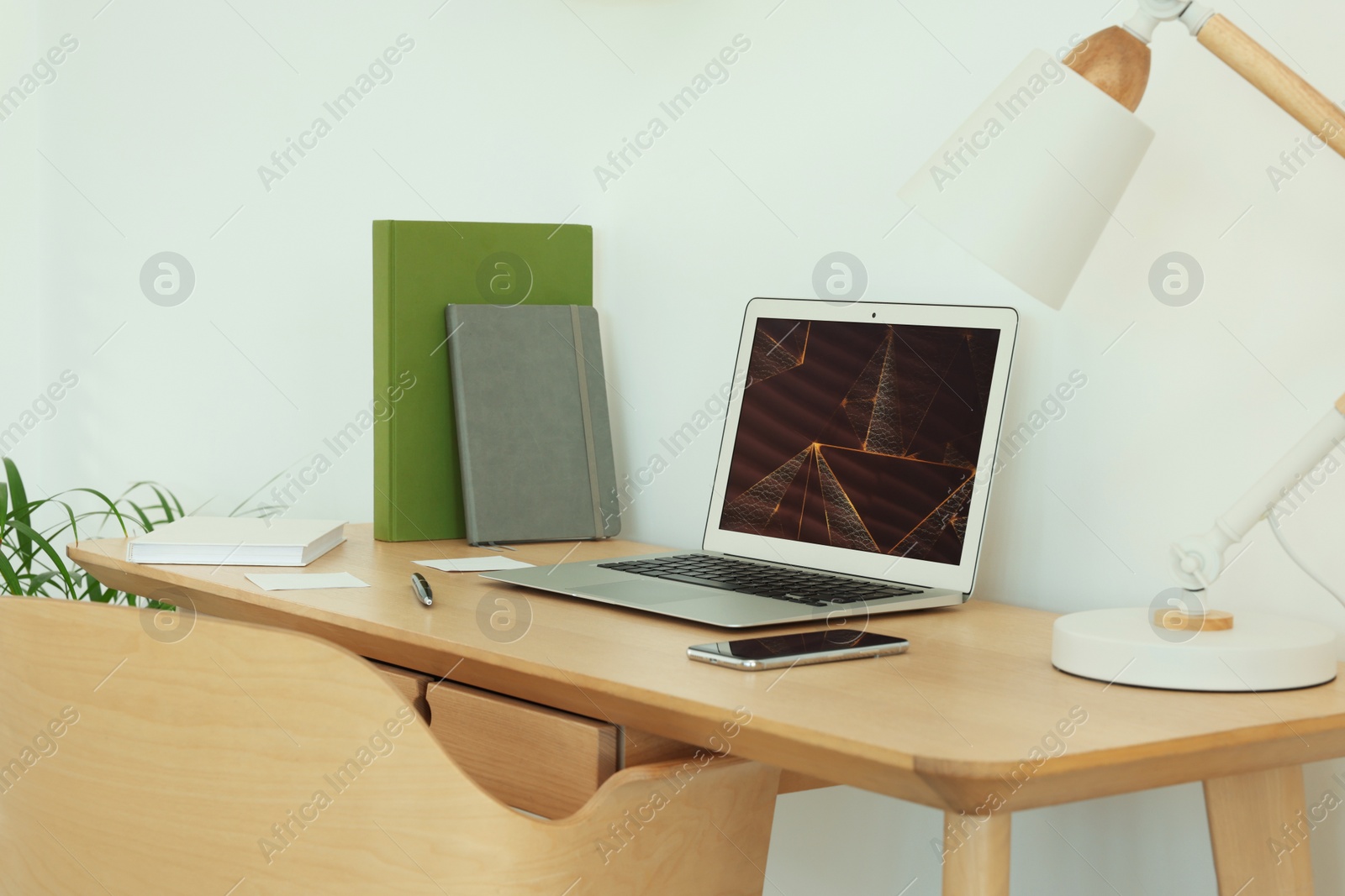 Photo of Cozy workspace with modern laptop on desk and comfortable chair at home